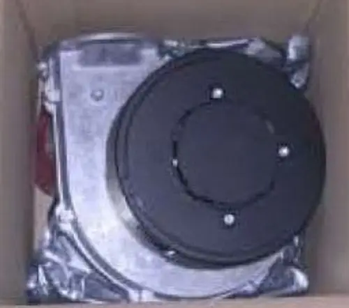 Brenner Gebläse von Remeha, in einem Karton verpackt. Die Konstruktion zeigt Metallteile und einen runden, schwarzen Abschnitt oben.